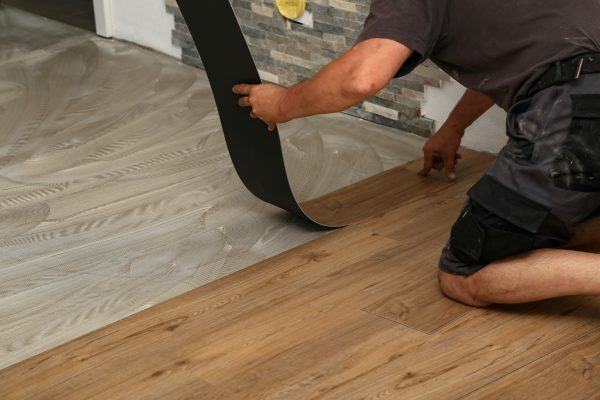 A low angle shot of a worker installing a new set of vinyl tiles on the floor