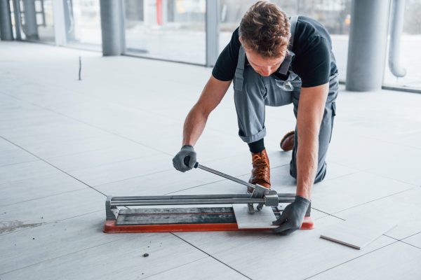 Man in grey uniform installing plate indoors in modern big office at daytime.